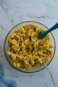mixing elbow macaroni and cheese sauce